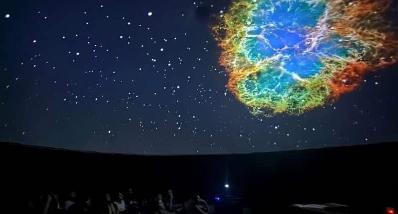 sala escura com projeção da galáxia no teto