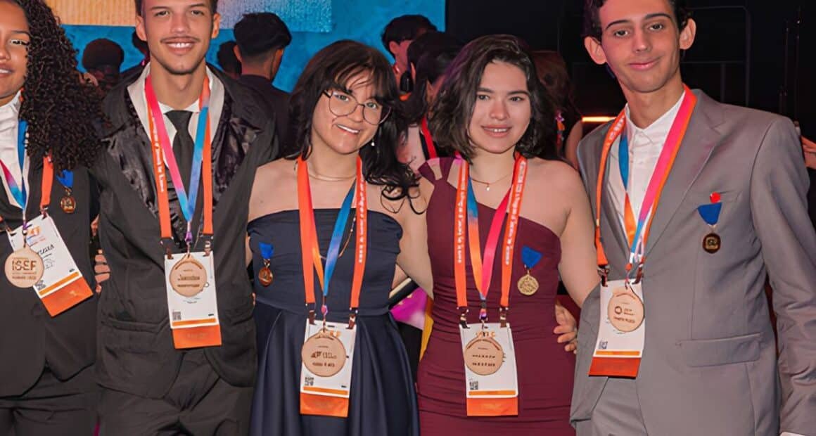 Quatro estudantes, sendo dois homens e duas mulheres em pé com medalhas no peito