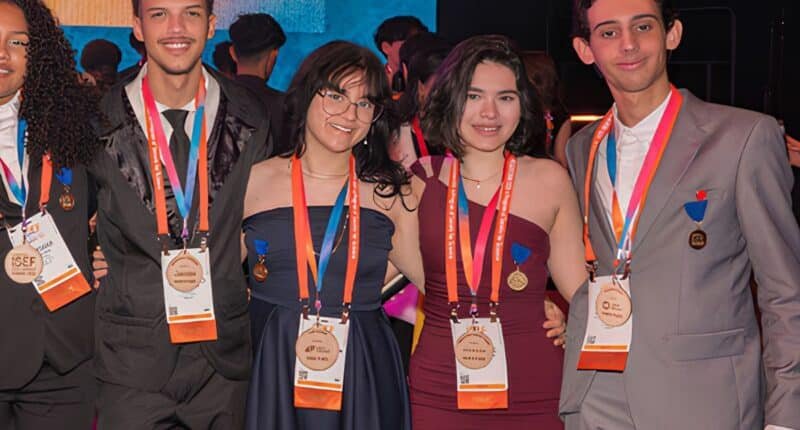 Quatro estudantes, sendo dois homens e duas mulheres em pé com medalhas no peito