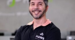 homem de braços cruzados em frente a logo da fpfetch