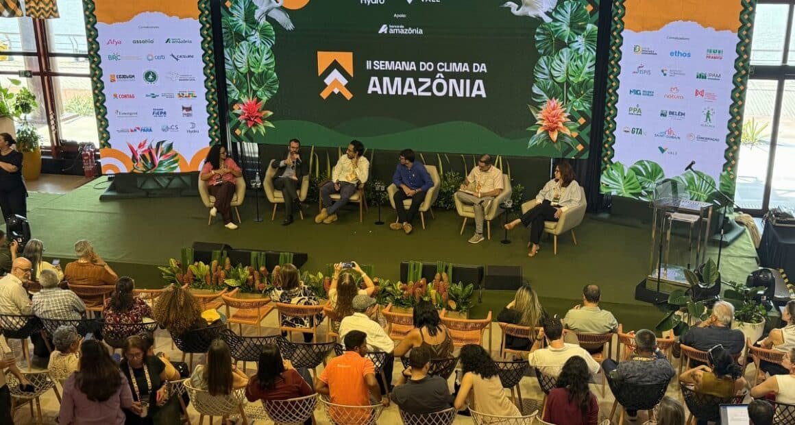 Um grupo de pessoas sentadas em um evento com pessoas no palco em belém