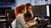 duas mulheres sentadas olhando para a tela de um computador