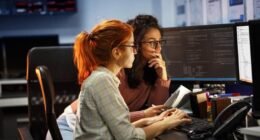 duas mulheres sentadas olhando para a tela de um computador
