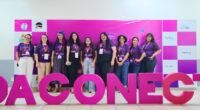 um grupo de mulheres atrás de uma placa escrita ada conecta