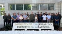 Pessoas em atrás de uma placa escrita instituto de pesquisas do exército na amazônia