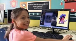menina sentada na frente do computador. ela usa camisa rosa