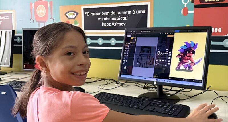 menina sentada na frente do computador. ela usa camisa rosa