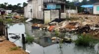 casa de madeira a beira de um igarapé com lixo nas margens